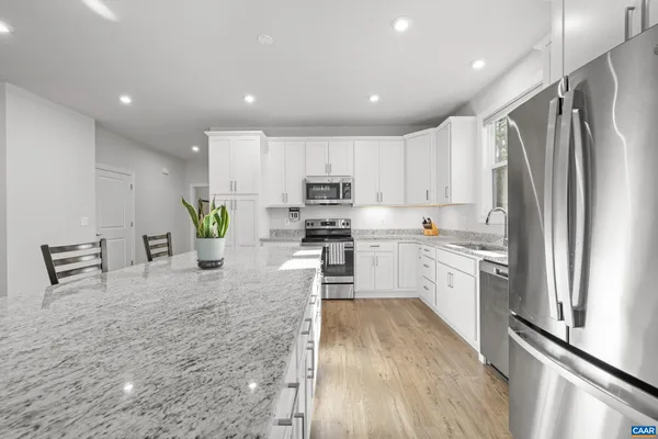 a large living room with stainless steel appliances granite countertop furniture and a wooden floor