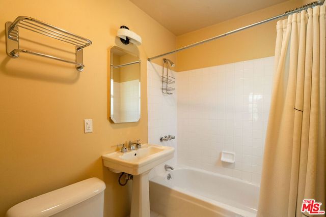 a bathroom with a sink and mirror with bathtub