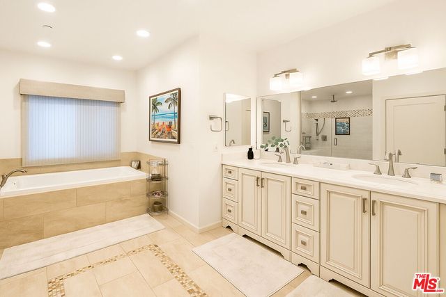 a spacious bathroom with a double vanity sink a mirror and a bathtub