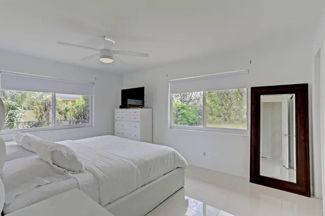 a large white bed in a room next to a window