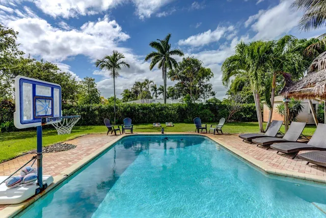 a view of swimming pool with lounge chair and dinning table under an umbrella