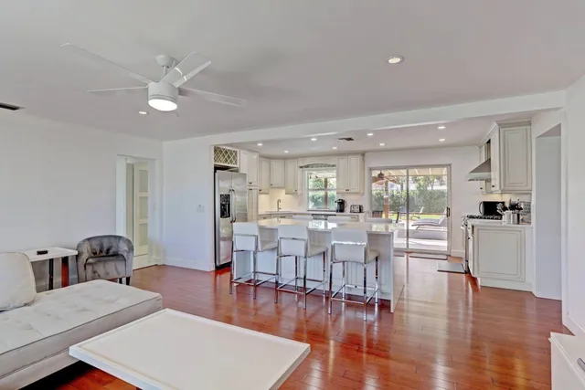 a living room with lots of furniture wooden floor and a large window