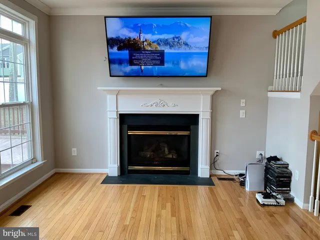 a view of an empty room with wooden floor fireplace and a window