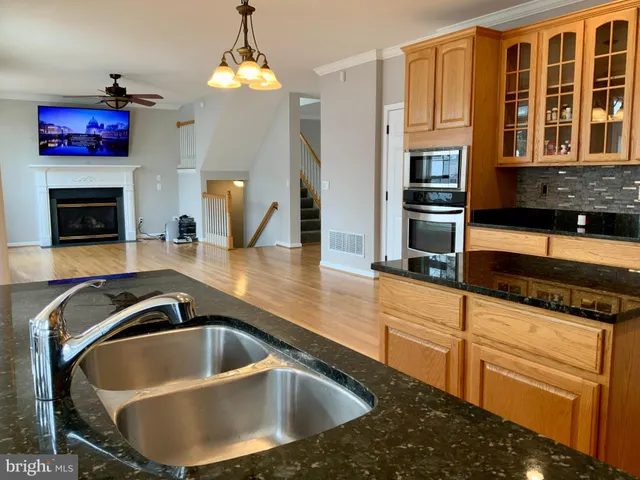 a kitchen with stainless steel appliances granite countertop a refrigerator a sink and white cabinets