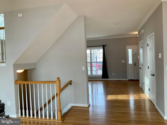 a view of an empty room and kitchen view with wooden floor