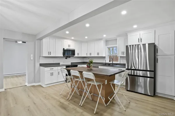a kitchen with stainless steel appliances granite countertop a refrigerator a sink dishwasher a stove and white cabinets with wooden floor