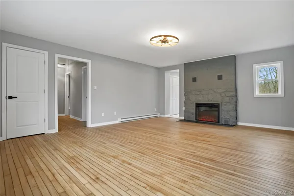 a view of empty room with wooden floor and fireplace