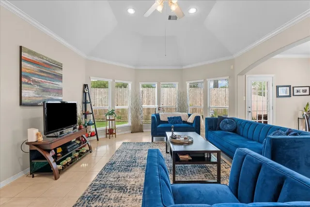 a living room with furniture a flat screen tv and a floor to ceiling window