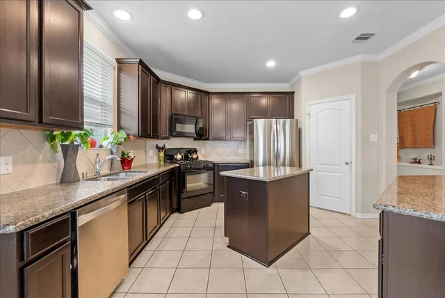 a kitchen with stainless steel appliances granite countertop a refrigerator a stove a sink a microwave and island