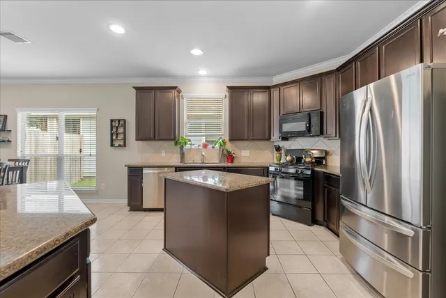 a kitchen with kitchen island granite countertop a refrigerator stove top oven and sink