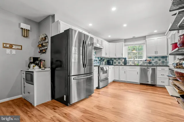 a kitchen with granite countertop a refrigerator stove and wooden floor