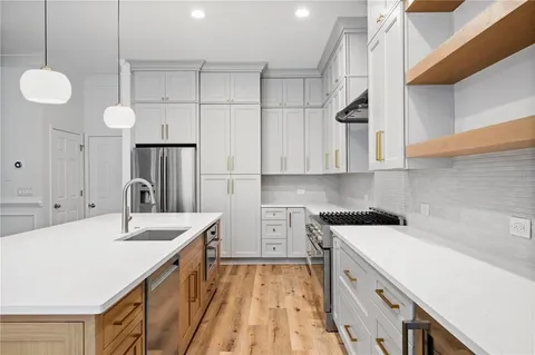a kitchen with a sink dishwasher and white cabinets with wooden floor