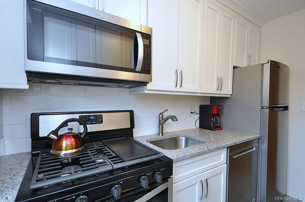 235 Garth Road, Unit A5B Scarsdale, NY 10583 - Photo 10 of 47 a kitchen with stainless steel appliances granite countertop a stove and a refrigerator