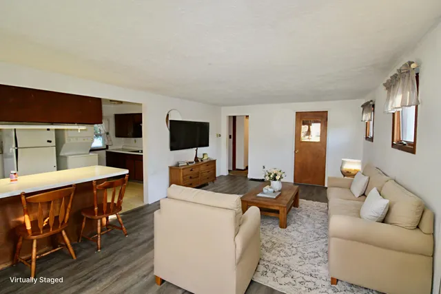 a living room with furniture a flat screen tv and kitchen view