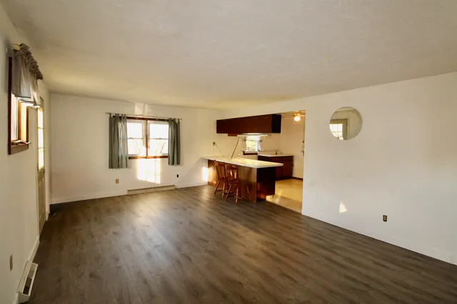 a view of an empty room with a window and wooden floor