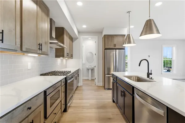 a kitchen with stainless steel appliances granite countertop a sink a stove and a refrigerator