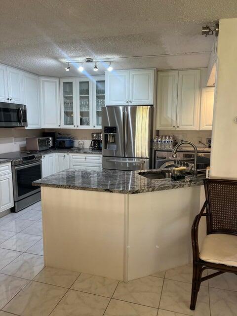 311 Pine Ridge Circle, Unit B1 Greenacres, FL 33463 - Photo 7 of 7 a kitchen with stainless steel appliances granite countertop a refrigerator a stove a sink a dining table and chairs