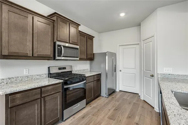 a kitchen with stainless steel appliances granite countertop a stove a sink and a refrigerator with wooden floor