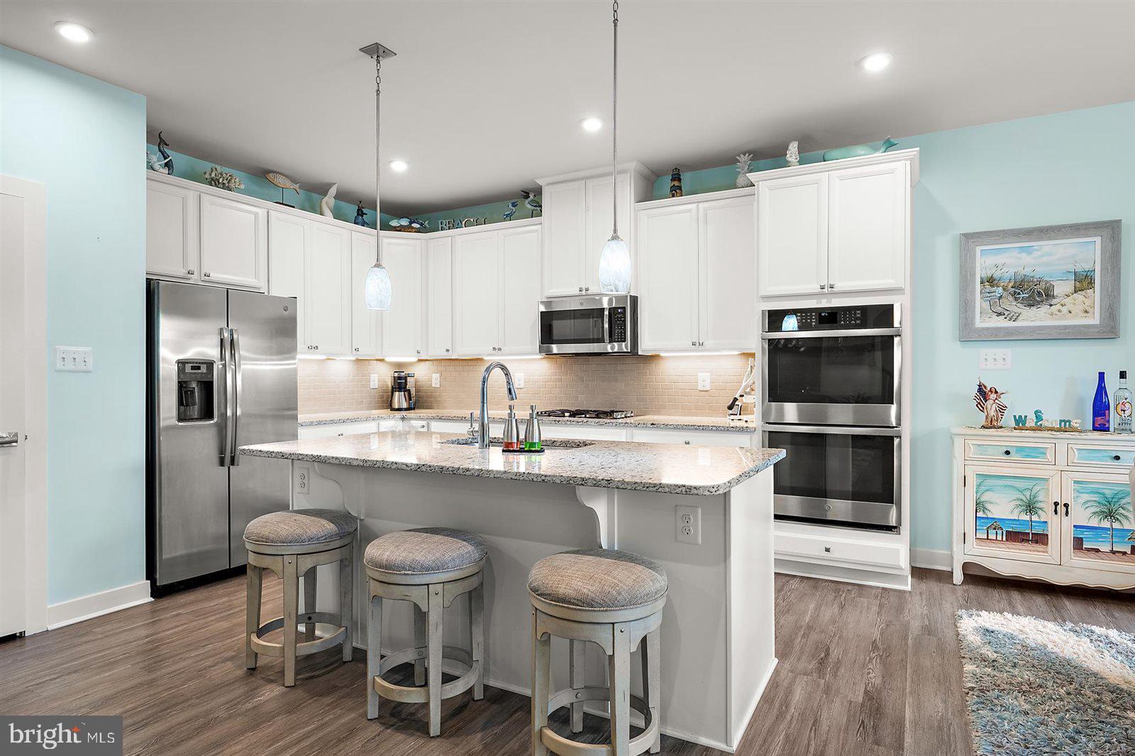 23546 Robalo Road Frankford, DE 19945 - Photo 25 of 78 a kitchen with stainless steel appliances a stove a sink dishwasher a refrigerator and a dining table with wooden floor