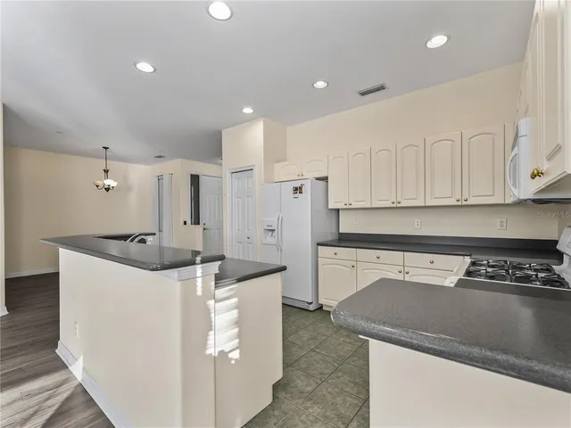 a view of an empty room with wooden floor and a kitchen