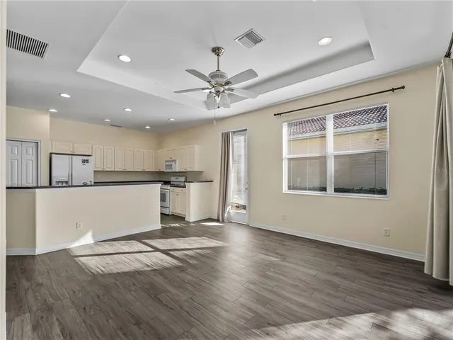 an empty room with windows and chandelier fan