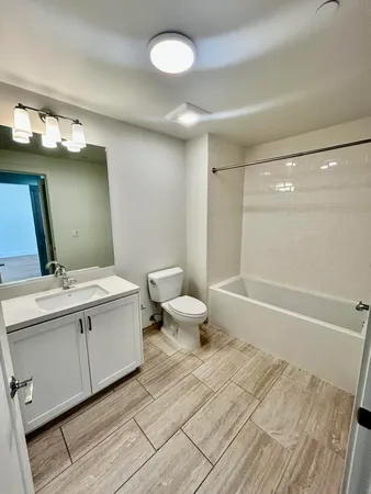 a bathroom with a double vanity sink toilet mirror and bathtub