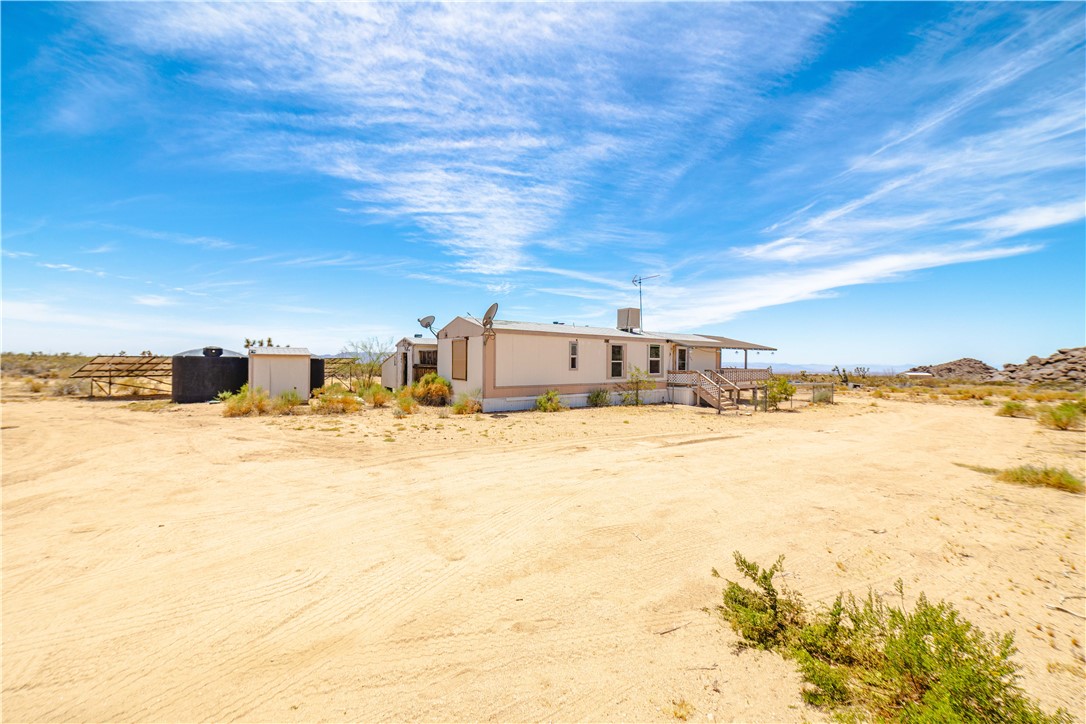 16435 South Wyatt Earp Road Yucca, AZ 86438 - Photo 52 of 57 Single-story residence featuring a covered porch, wood exterior stairs, and a light-colored fa?ade