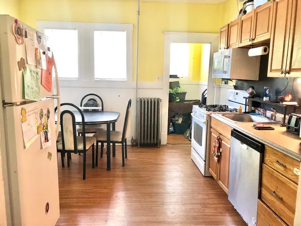a kitchen with stainless steel appliances granite countertop a stove top oven a sink a dining table and chairs with wooden floor