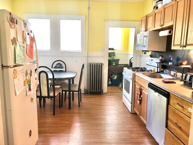 a kitchen with stainless steel appliances granite countertop a stove top oven a sink a dining table and chairs with wooden floor