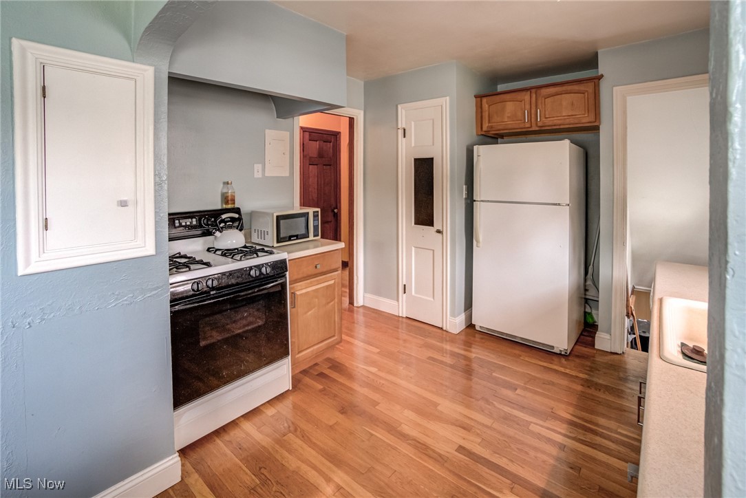1264 Avondale Road Cleveland, OH 44121 - Photo 15 of 25 Kitchen with white appliances, light wood-style floors, light countertops, and brown cabinets