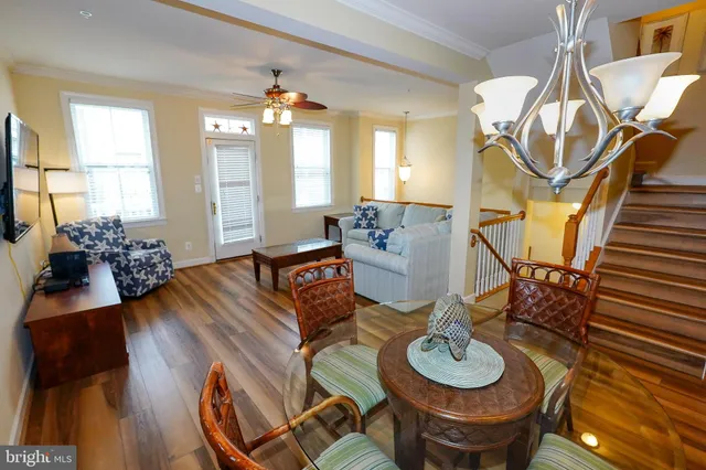 a kitchen with a stove a refrigerator a sink a dining table and chairs with wooden floor