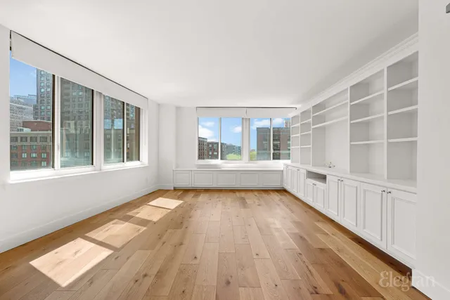 a view of an empty room with wooden floor and windows