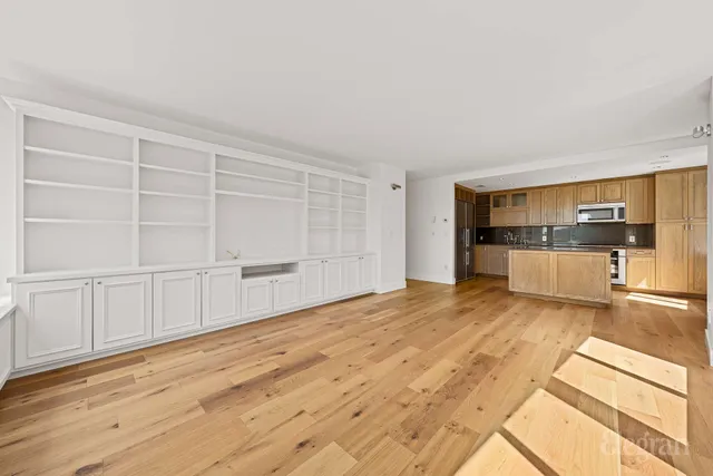 a view of a kitchen with wooden cabinet and an empty room