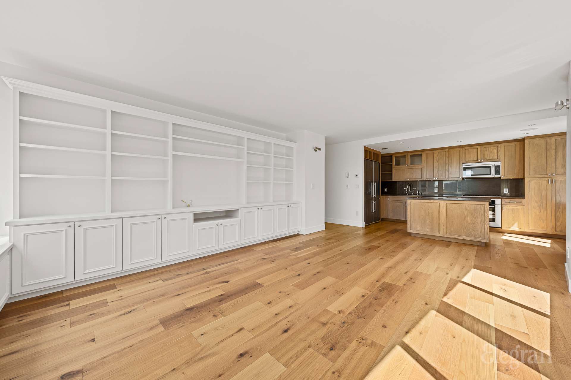 333 Rector Place, Unit 805 Manhattan, NY 10280 - Photo 5 of 28 a view of a kitchen with wooden cabinet and an empty room