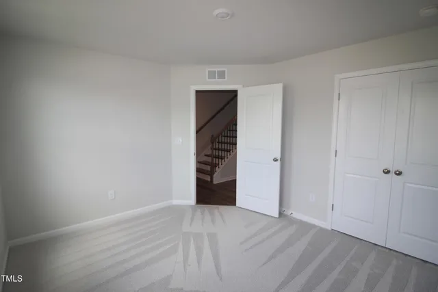 a view of an empty room with wooden floor and closet