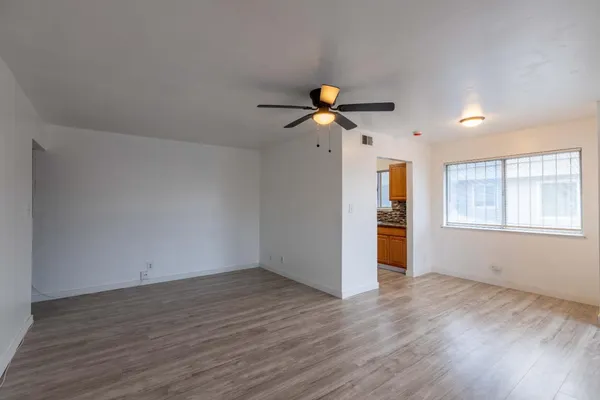 a view of an empty room with a window and wooden floor