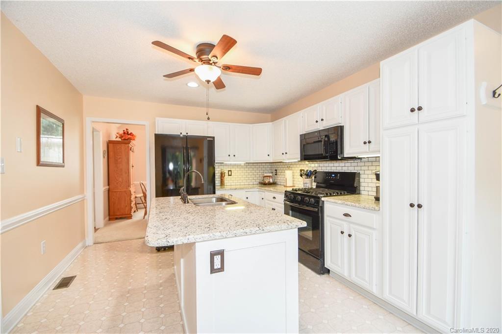 3400 Helms Pond Road Monroe, NC 28110 - Photo 15 of 24 a kitchen with granite countertop a refrigerator a sink dishwasher stove and white cabinets with wooden floor