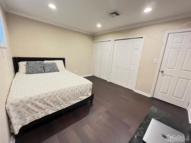 a large bed in a white room with wooden floor