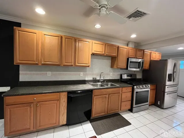 a kitchen with stainless steel appliances granite countertop a sink a stove a refrigerator cabinets and a window