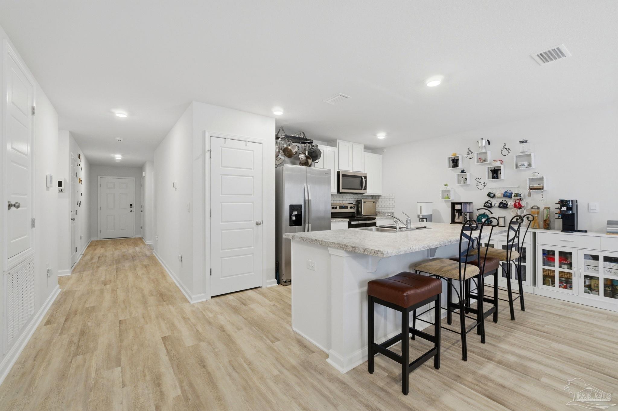 6126 Native Dancer Way Pensacola, FL 32526 - Photo 21 of 40 a kitchen with stainless steel appliances a refrigerator and a wooden floor