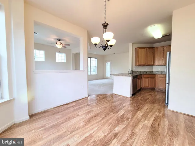 a view of a kitchen with a sink dishwasher and a refrigerator with wooden floor
