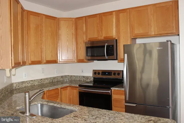 a kitchen with granite countertop a refrigerator stove and microwave