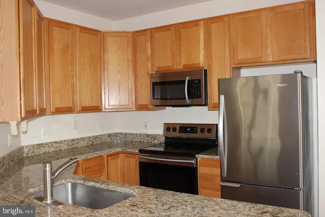 a kitchen with granite countertop a refrigerator stove and microwave
