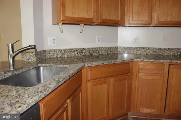 a kitchen with granite countertop a sink a stove and cabinets