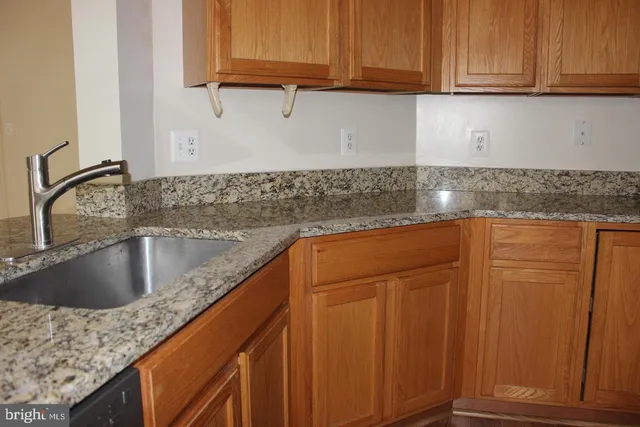 a kitchen with granite countertop a sink a stove and cabinets