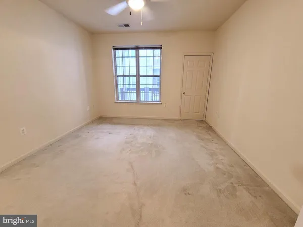 an empty room with windows and chandelier fan