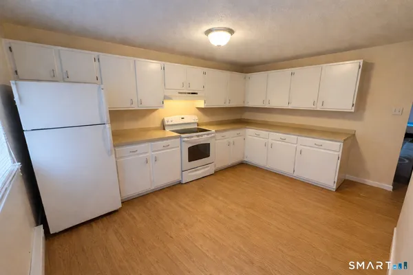 a kitchen with white cabinets and white appliances