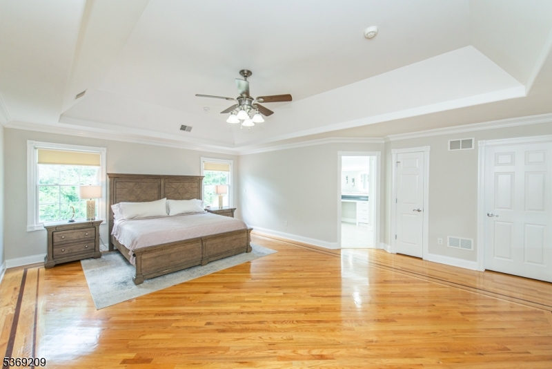 6 Perin Place Succasunna, NJ 07876 - Photo 21 of 39 a spacious bedroom with a large bed a chandelier and wooden floor