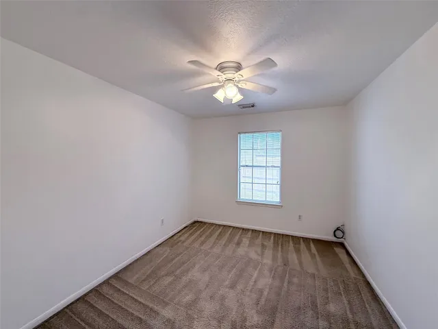 an empty room with a window and a fan