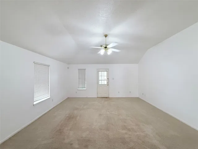 en empty room with windows and chandelier fan